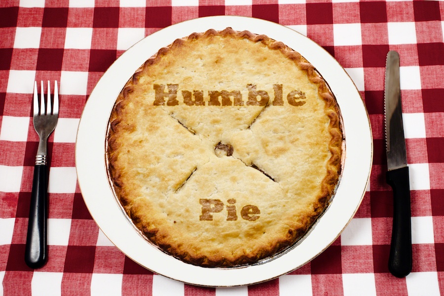 pie sitting on white plate on a red and white gingham tablecloth, with a fork on the left and a knife on the right.